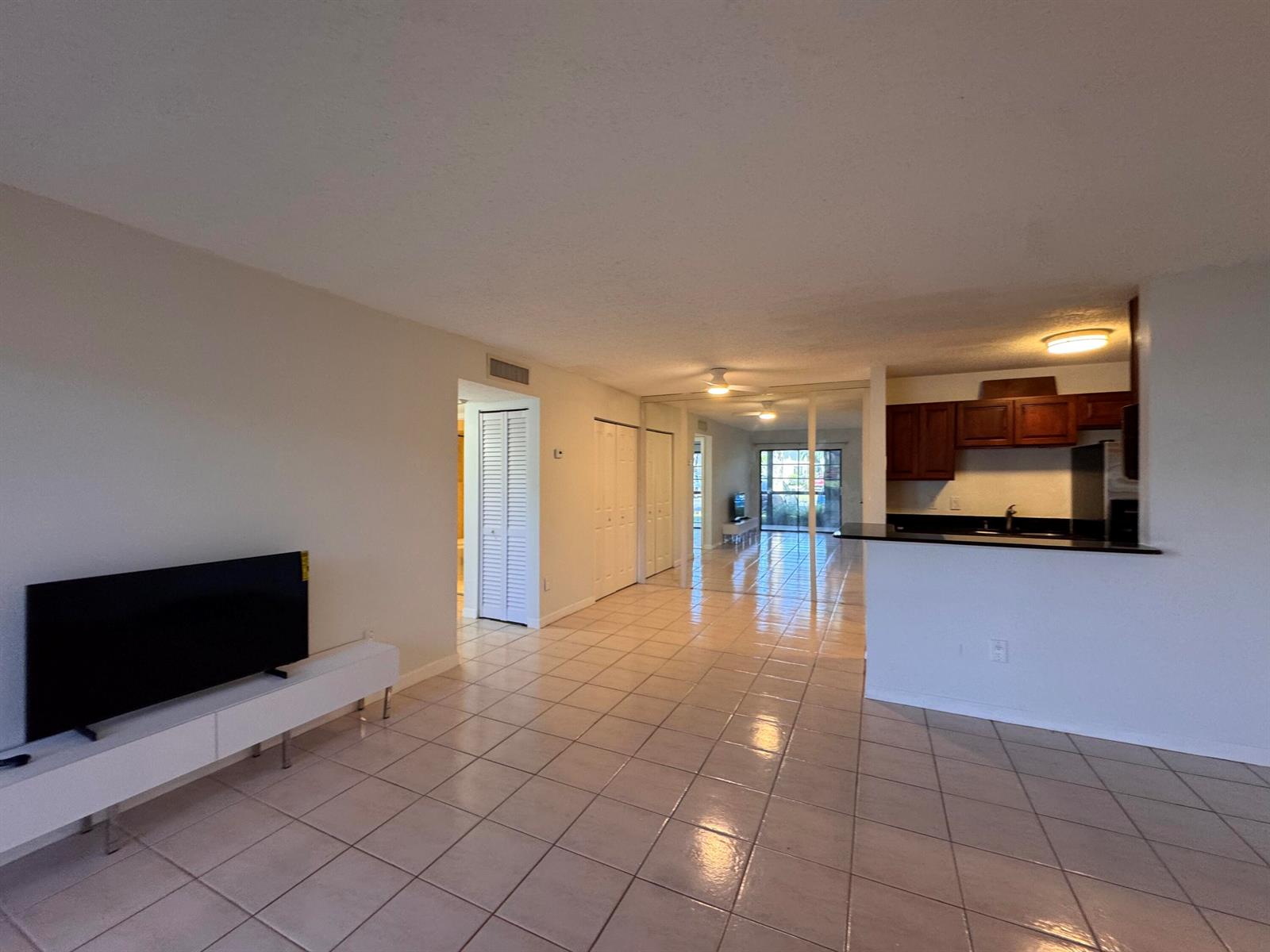 An open-concept living area with tile flooring, a kitchen counter, and a television stand — 809 NE 199th Street # 7, Miami FL 33179, MIAMI, FL