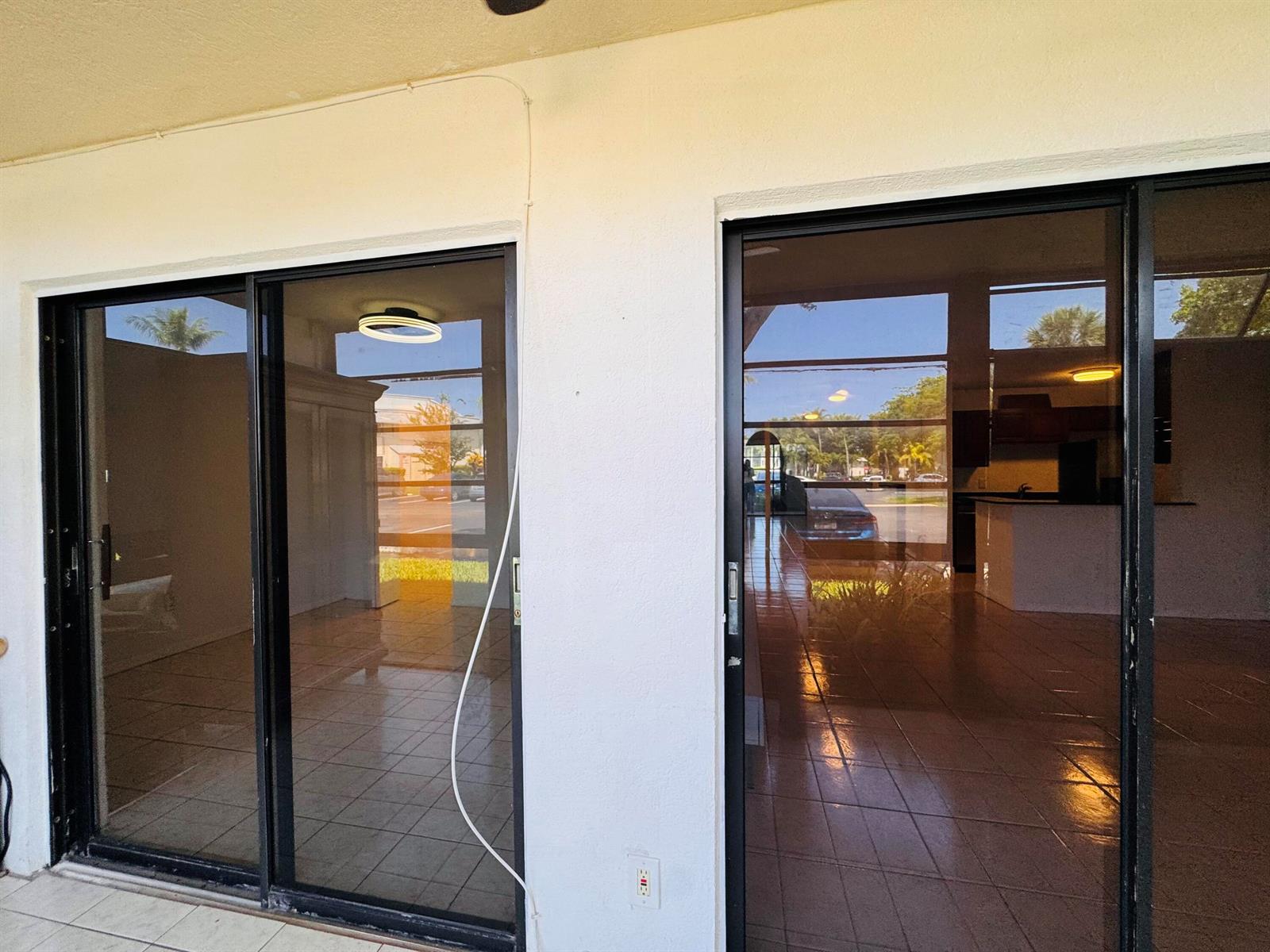 Two sliding glass doors open into a tiled interior space with a kitchen visible — 809 NE 199th Street # 7, Miami FL 33179, MIAMI, FL
