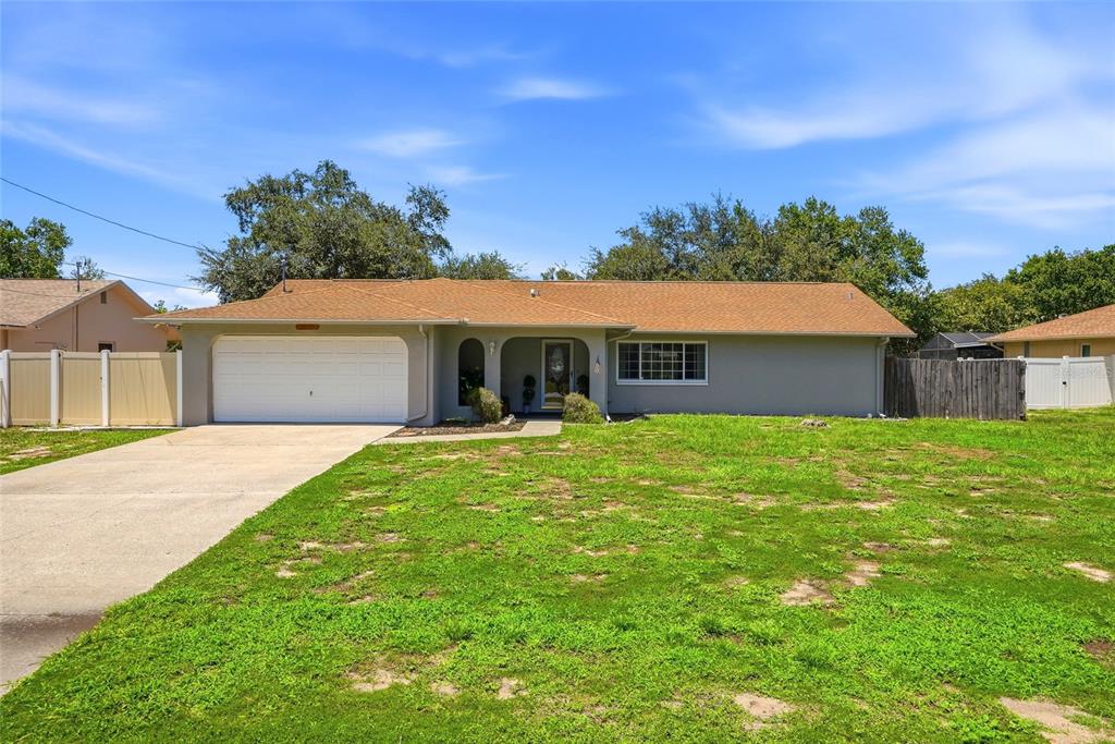 A single-story house with a tan roof, gray exterior, and a two-car garage — 10435 TASSEL STREET, SPRING HILL, FL