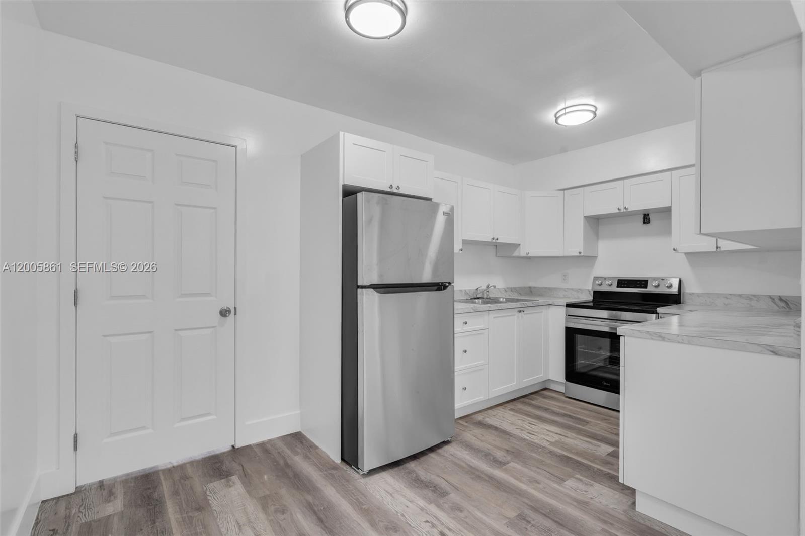 A white door opens to a concrete patio area with a carport and metal fencing — 265 NE 55th Ter # 1, Miami FL 33137, MIAMI, FL