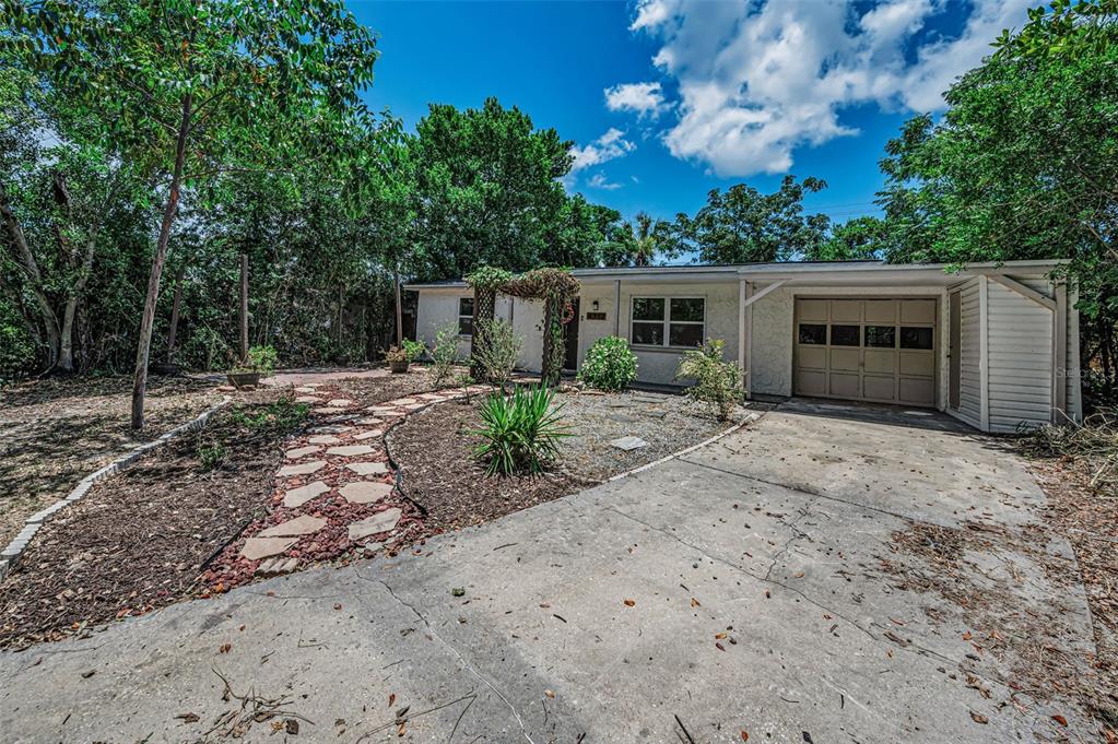 A single-story house with a white exterior, a concrete driveway, and a stone walkway — 4312 BEACON SQUARE DRIVE, HOLIDAY, FL