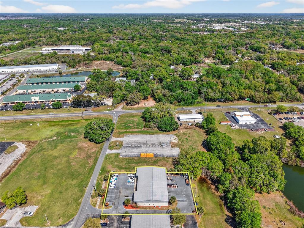 An aerial view shows a commercial warehouse building with a parking lot and surrounding land — 300 RICHEY ROAD, LEESBURG, FL