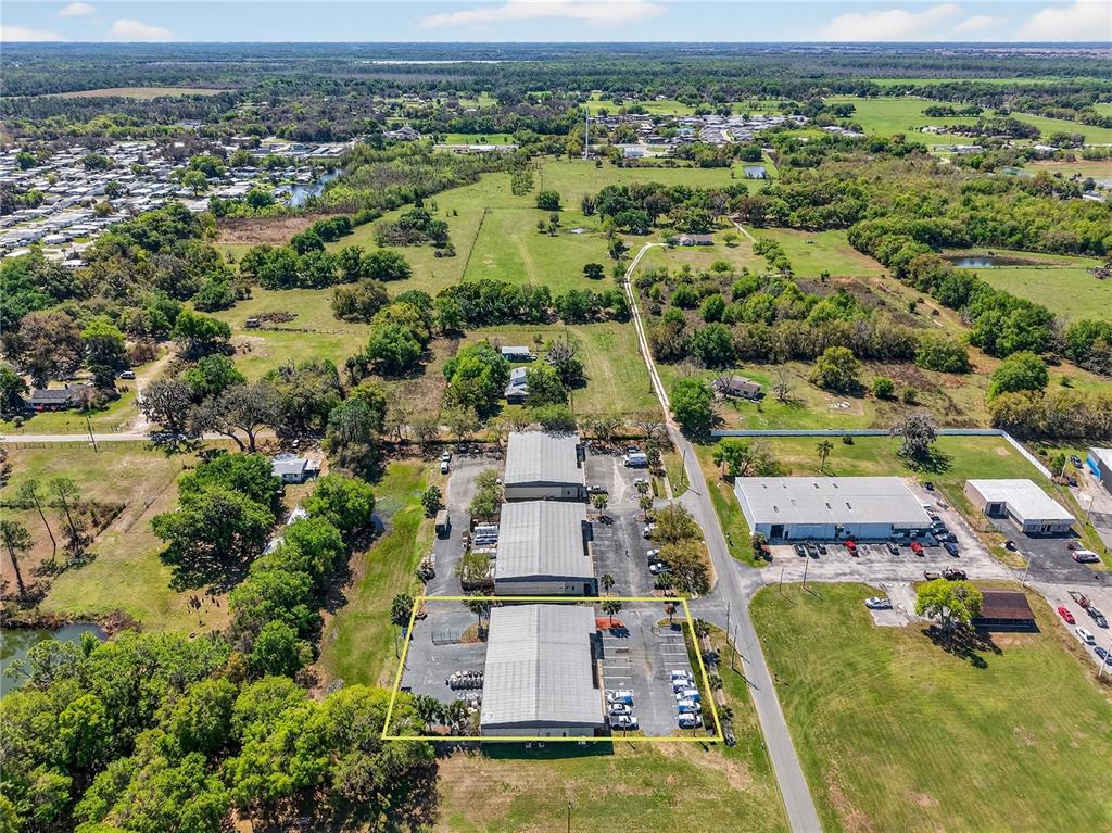 An aerial view shows a commercial warehouse complex with parking lots surrounded by rural land — 300 RICHEY ROAD, LEESBURG, FL