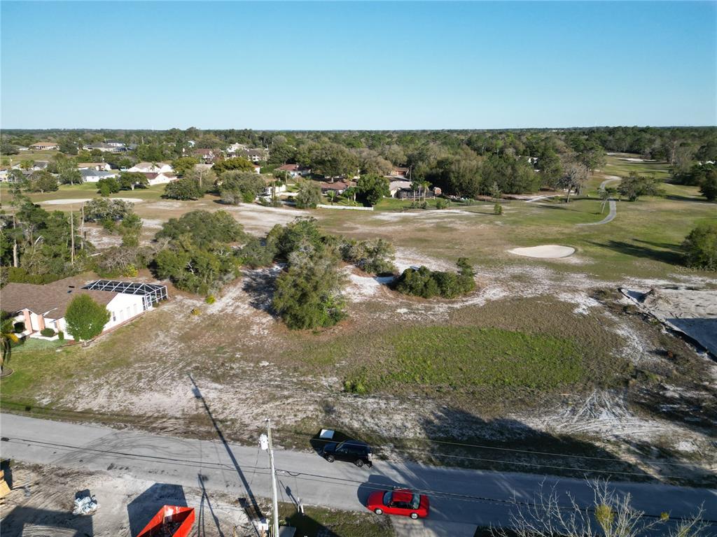 An aerial view shows a vacant, sandy residential lot adjacent to a golf course — KIRKWOOD AVENUE, SPRING HILL, FL
