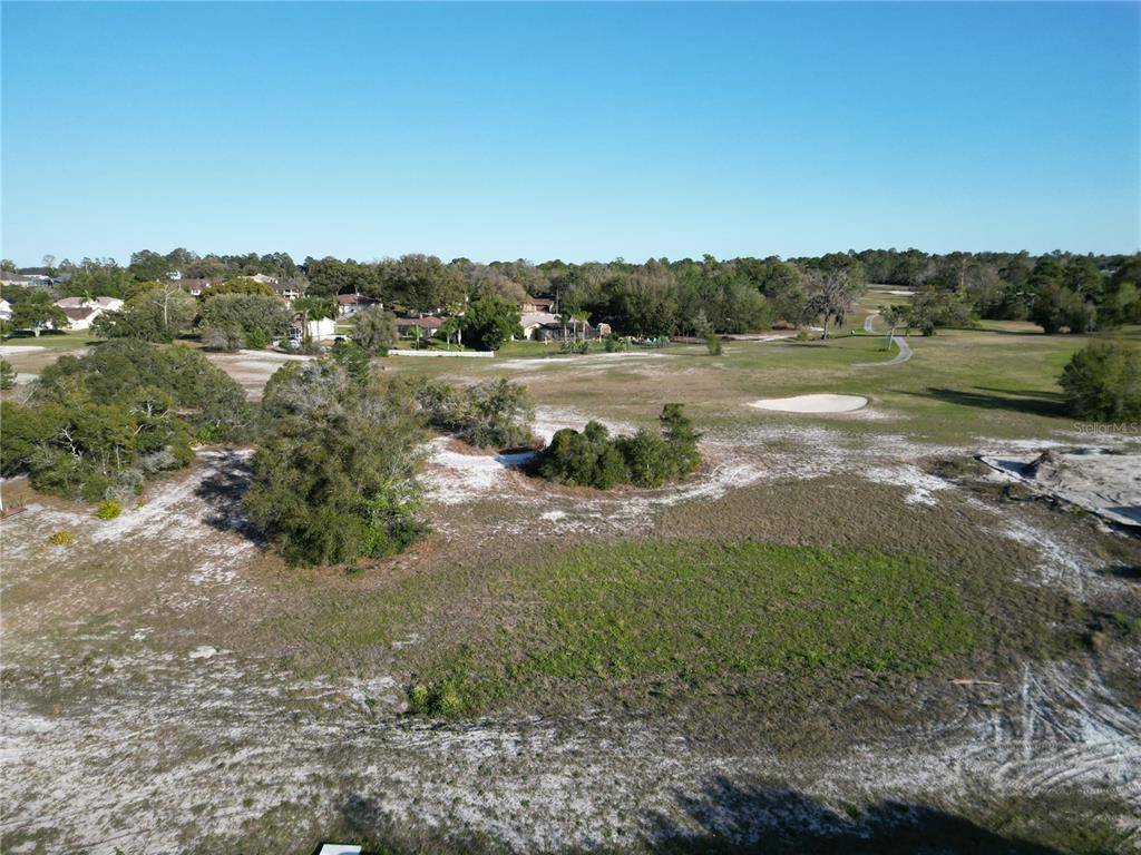 An aerial view shows a sandy, partially cleared lot bordering a golf course and houses — KIRKWOOD AVENUE, SPRING HILL, FL