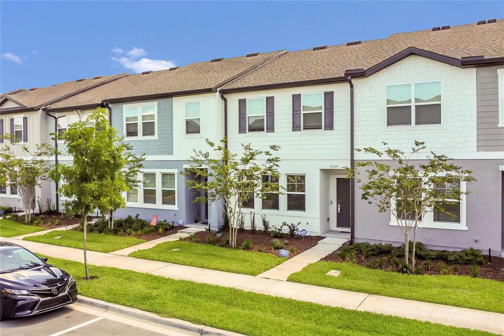 A row of modern townhomes with light-colored siding and a dark gray front door — 3335 AZOLLA STREET, ORLANDO, FL