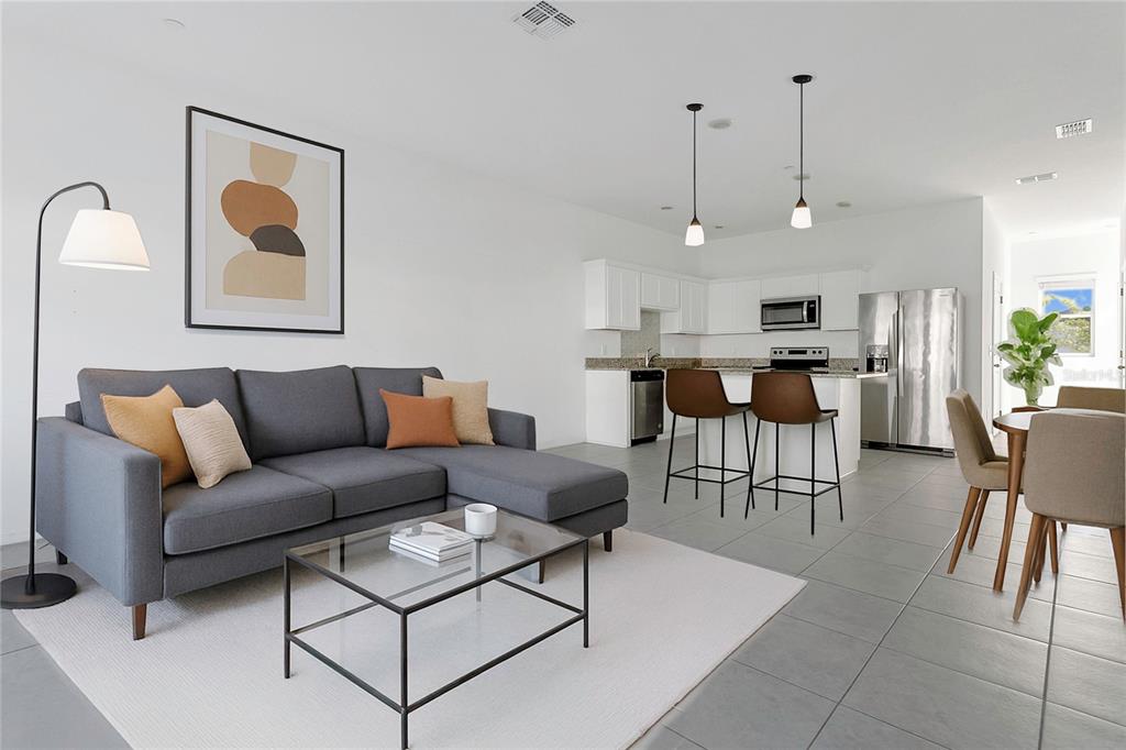 An open-concept living area features a gray sectional sofa, glass coffee table, and kitchen island — 3335 AZOLLA STREET, ORLANDO, FL