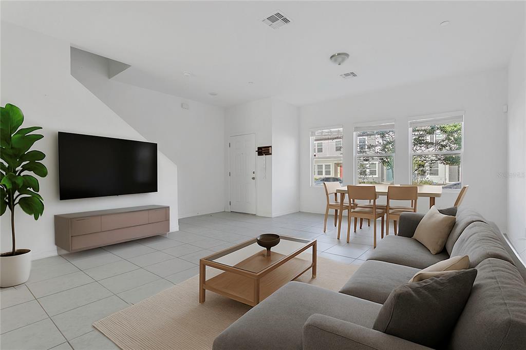 A living room with tile floors, a gray sectional sofa, a television, and a dining area — 3335 AZOLLA STREET, ORLANDO, FL