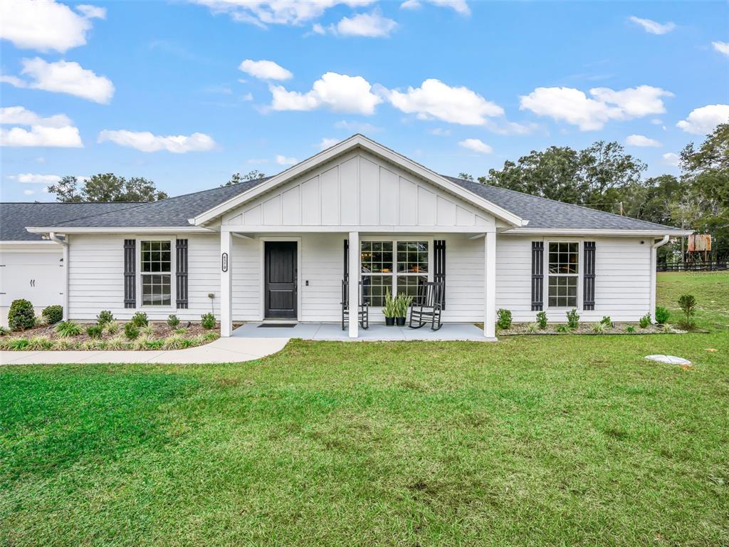 A white single-story house with a covered front porch, black shutters, and a dark door — 6570 SE 175TH COURT, MORRISTON, FL
