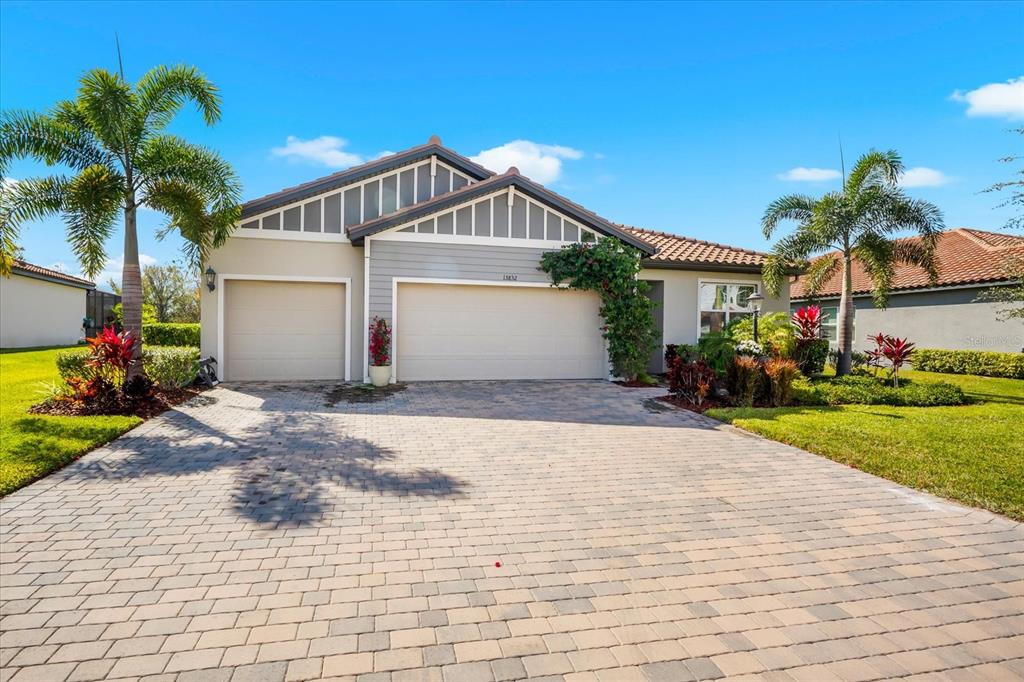 A single-story house with a paved driveway, two garage doors, and palm trees — 13832 GREEN HAMMOCK PLACE, BRADENTON, FL