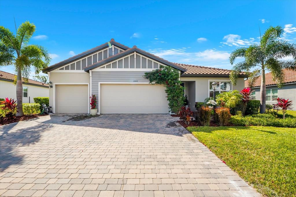 A single-story house with a paved driveway, a three-car garage, and palm trees — 13832 GREEN HAMMOCK PLACE, BRADENTON, FL