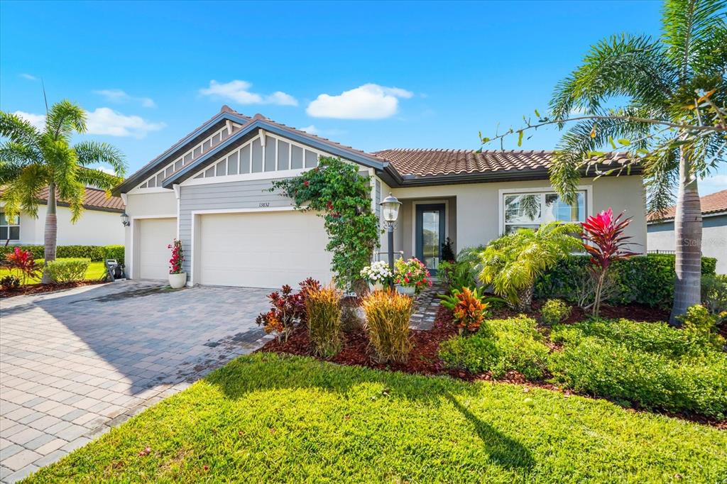 A single-story house with a paved driveway, a two-car garage, and landscaped front yard — 13832 GREEN HAMMOCK PLACE, BRADENTON, FL