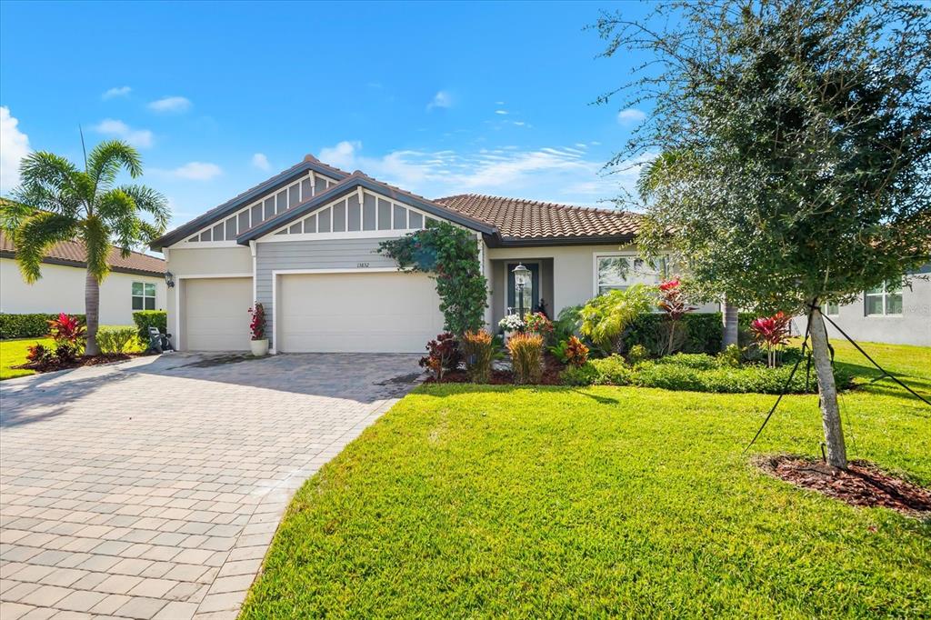 A single-story house with a two-car garage, a paved driveway, and a landscaped front yard — 13832 GREEN HAMMOCK PLACE, BRADENTON, FL