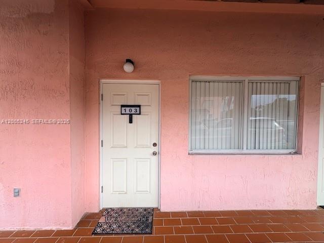 A pink exterior wall features a white door labeled 103 and a window with blinds — 8019 Lake Dr # 103, Doral FL 33166, DORAL, FL