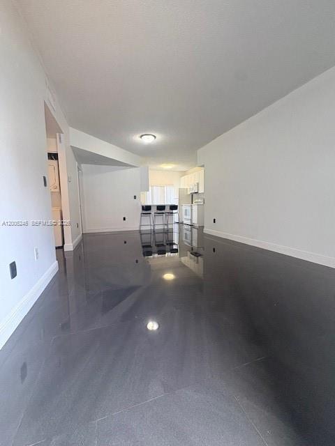 An open-concept living area features dark, glossy flooring and a view toward a kitchen — 8019 Lake Dr # 103, Doral FL 33166, DORAL, FL