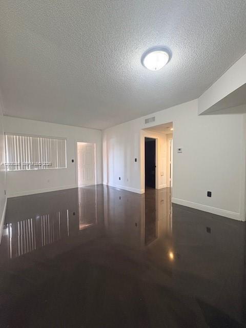 An empty room features white walls, a textured ceiling, and a dark, reflective floor — 8019 Lake Dr # 103, Doral FL 33166, DORAL, FL