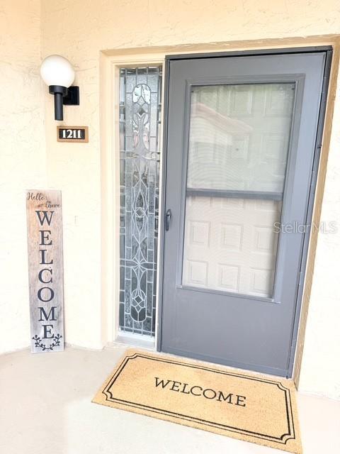 A front door with a glass storm door, a welcome sign, and a welcome mat — 1211 SALERNO COURT UNIT 1211, ORLANDO, FL
