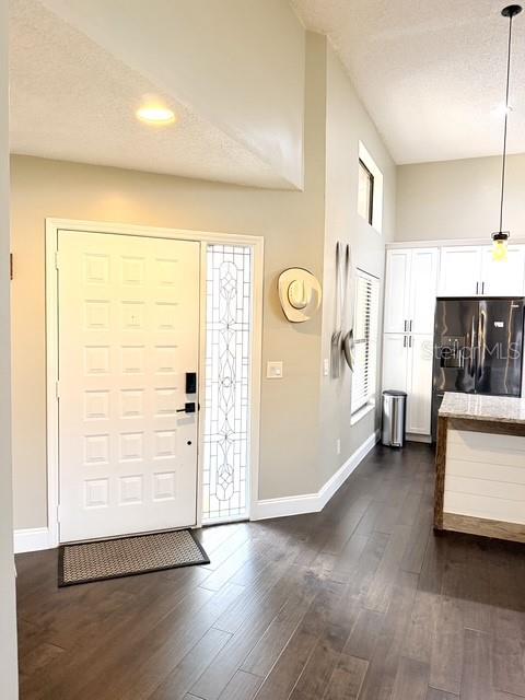 An entryway with a white front door, dark wood flooring, and an adjacent kitchen area — 1211 SALERNO COURT UNIT 1211, ORLANDO, FL