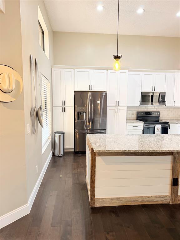 A kitchen features white cabinets, stainless steel appliances, a granite-topped island, and dark wood flooring — 1211 SALERNO COURT UNIT 1211, ORLANDO, FL