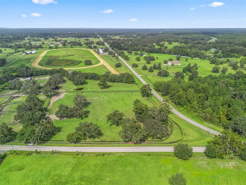 An aerial view shows a large rural property with pastures, a racetrack, and surrounding trees — TBD NW 110TH AVE, OCALA, FL