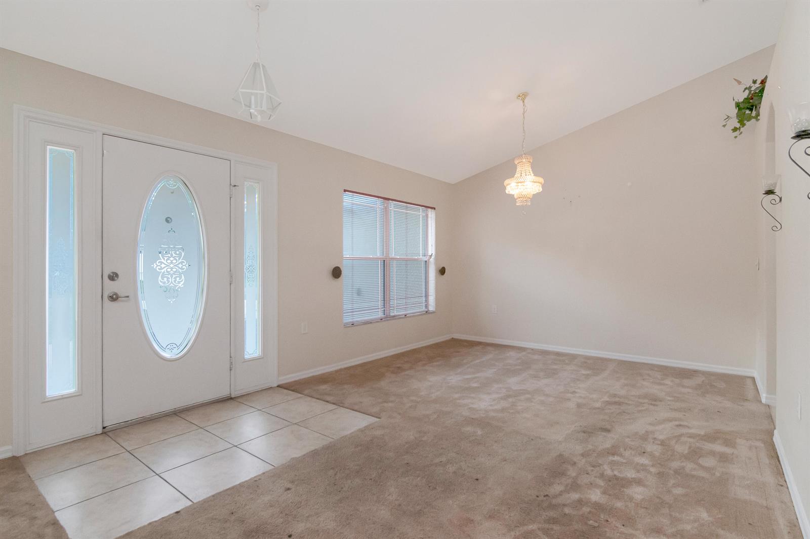An entryway with tiled flooring leads into a carpeted room featuring a vaulted ceiling — 12276 N Villa Road, Spring Hill FL 34609, SPRING HILL, FL