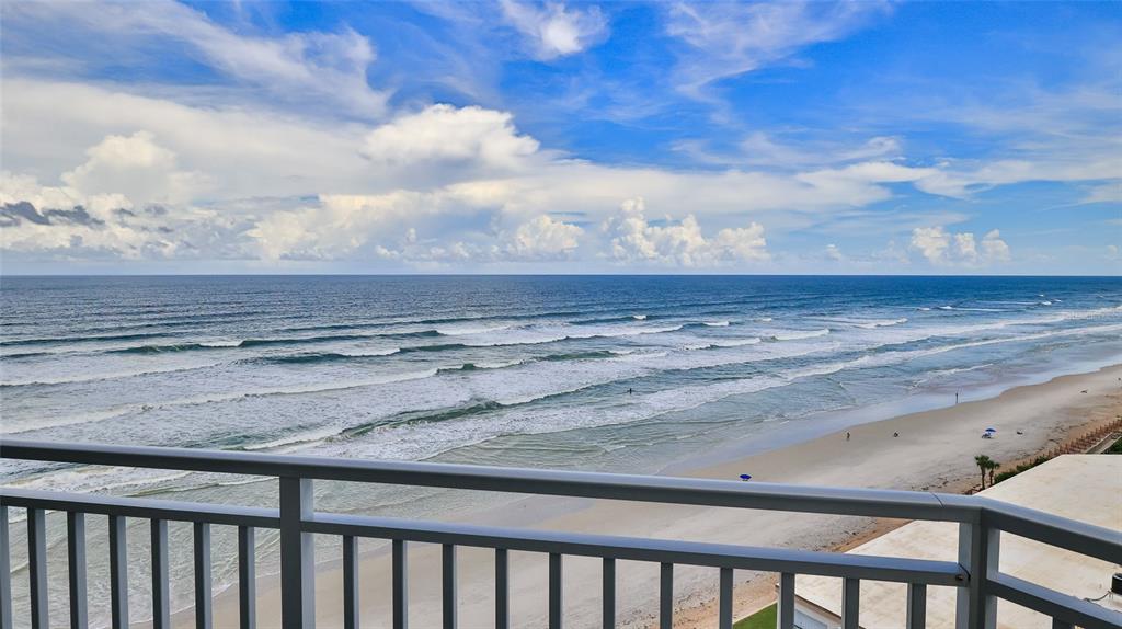 A balcony with a metal railing overlooks a sandy beach and the ocean under clouds — 5207 S ATLANTIC AVENUE UNIT 1226, NEW SMYRNA BEACH, FL