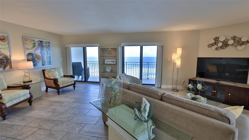 A living room features tile floors, a sofa, armchairs, and sliding doors overlooking the ocean — 5207 S ATLANTIC AVENUE UNIT 1226, NEW SMYRNA BEACH, FL