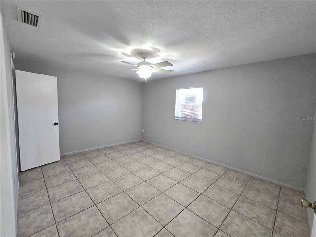 An empty bedroom features light gray walls, a white ceiling fan, and beige tile flooring — 5422 AMY LANE, NEW PORT RICHEY, FL