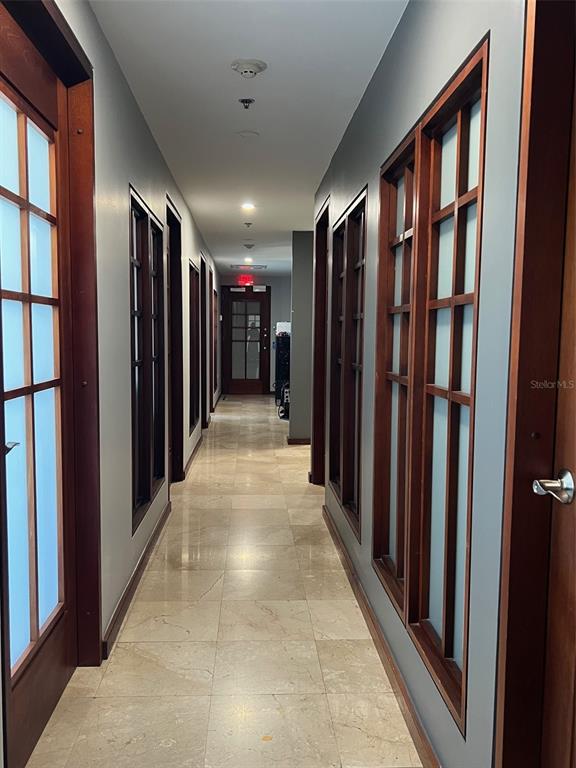 A long hallway features light-colored tile flooring, gray walls, and multiple dark wood-framed glass doors — 1509 LOPEZ LANDRON, SAN JUAN, PR