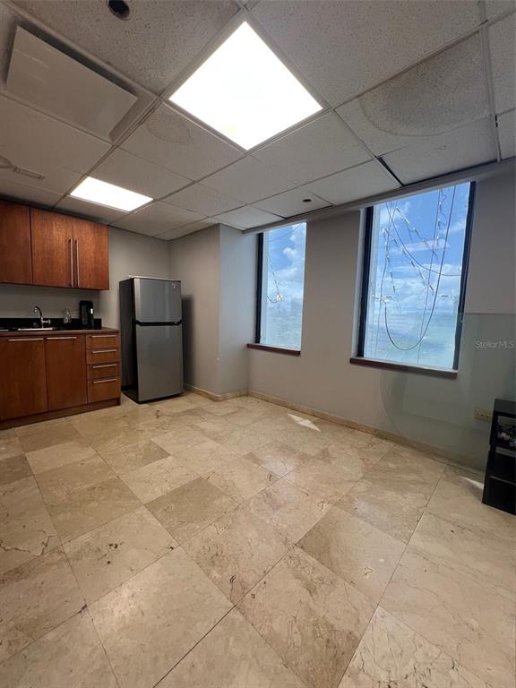 An office breakroom features wood cabinetry, a stainless steel refrigerator, tile flooring, and two windows — 1509 LOPEZ LANDRON, SAN JUAN, PR