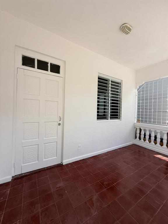 A covered porch features white walls, a white paneled door, a window, and red tiles — 513 BARBE STREET UNIT 101, SAN JUAN, PR