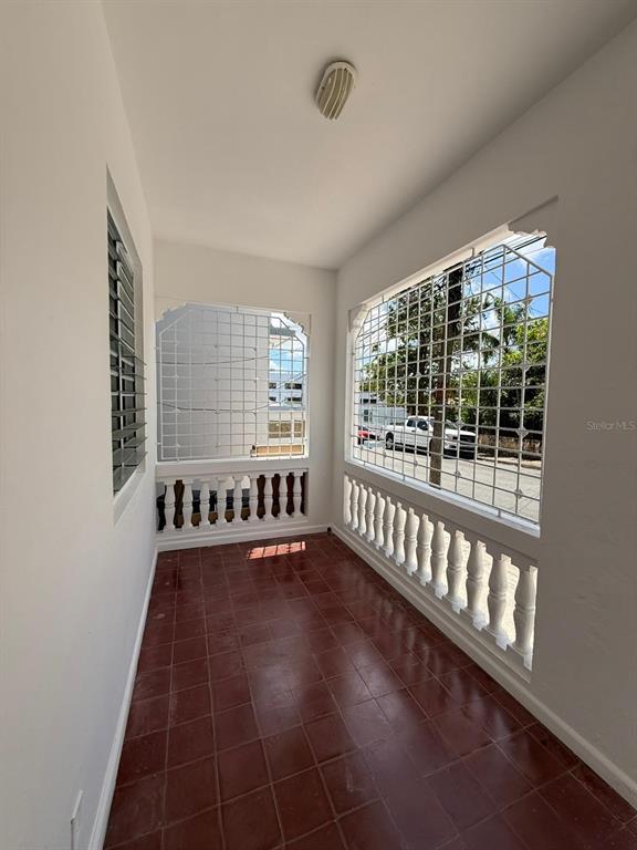 A covered balcony with red tile flooring, white balustrades, and metal security grilles on windows — 513 BARBE STREET UNIT 101, SAN JUAN, PR