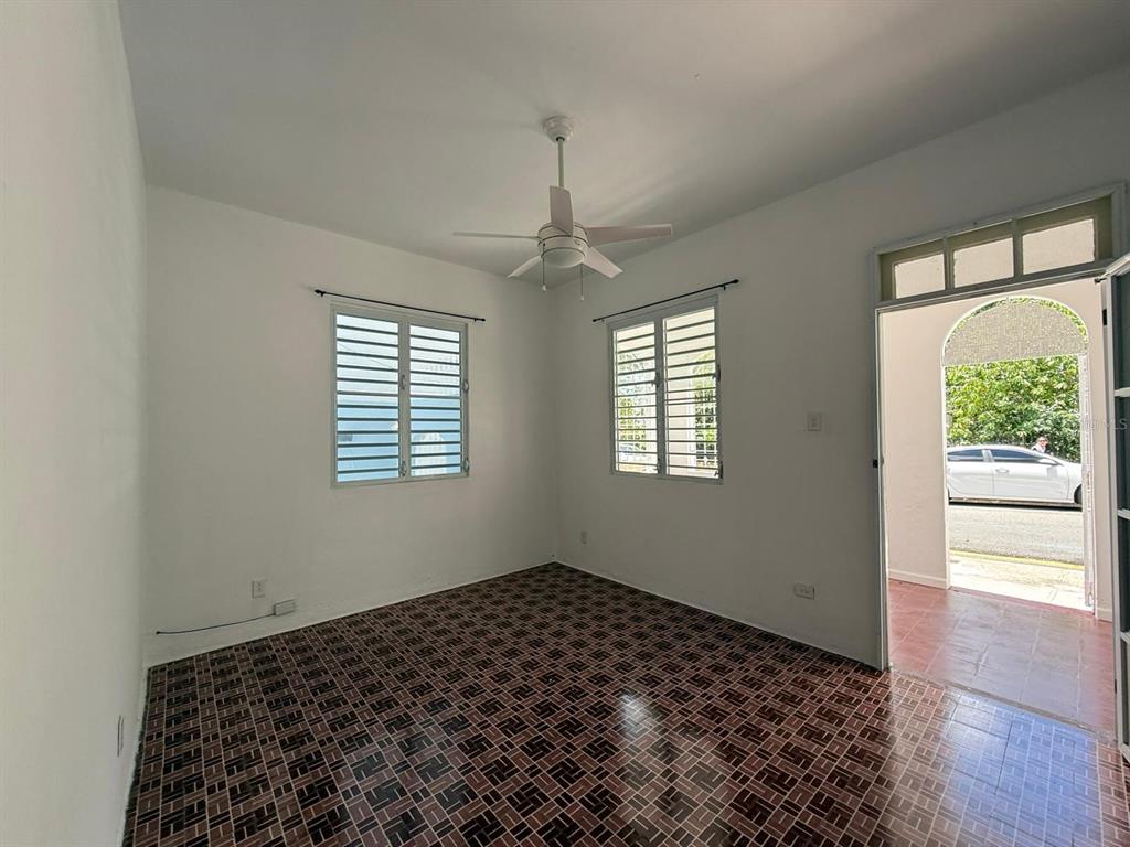 An empty room with tiled floors, a ceiling fan, and two windows facing outdoors — 513 BARBE STREET UNIT 101, SAN JUAN, PR