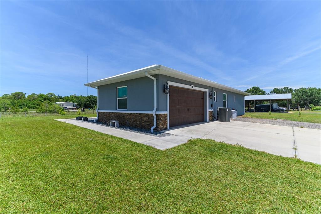 A gray detached garage with stone veneer siding sits on a grassy lot — 40200 LITTLE FARM ROAD, PUNTA GORDA, FL