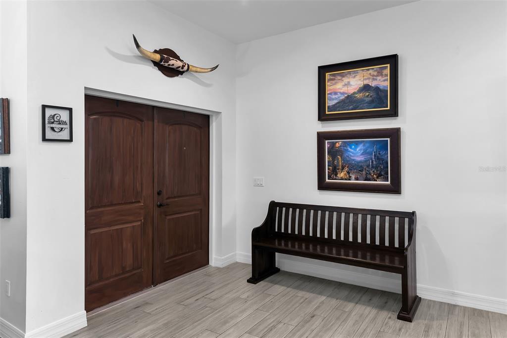 An entryway features a double wooden door, a wooden bench, and wall-mounted artwork — 40200 LITTLE FARM ROAD, PUNTA GORDA, FL