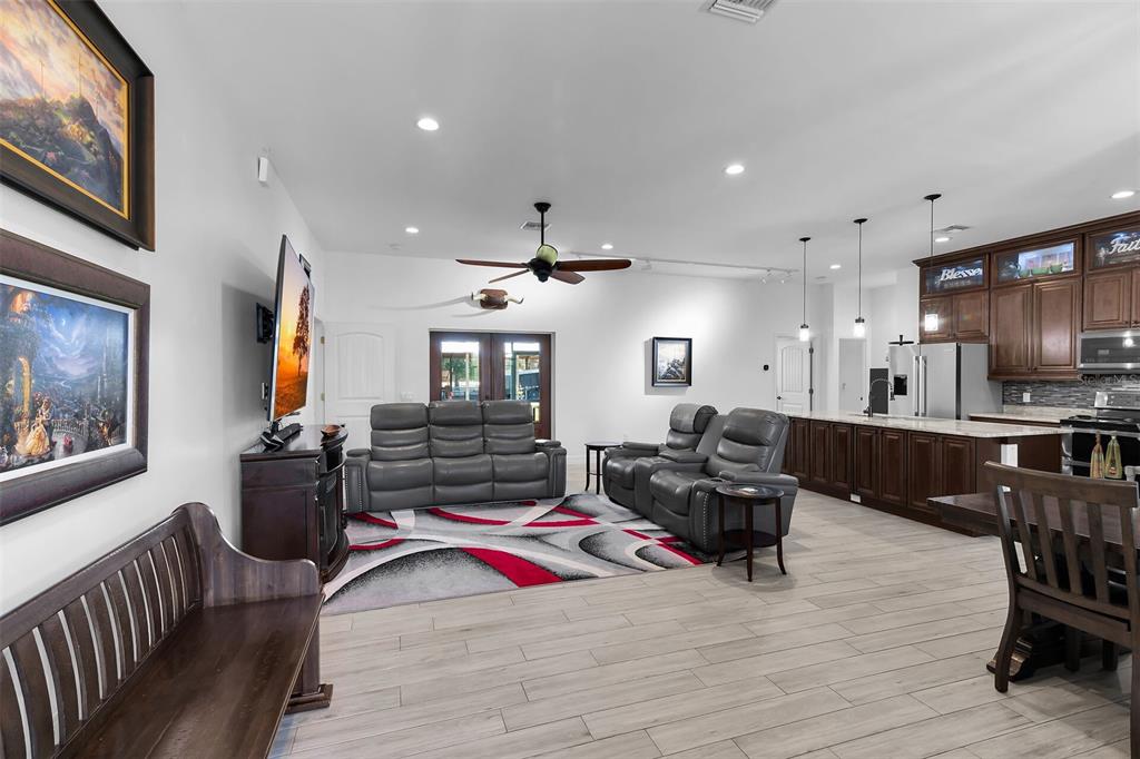 An open-concept living room and kitchen featuring grey tile floors, leather furniture, and dark cabinetry — 40200 LITTLE FARM ROAD, PUNTA GORDA, FL