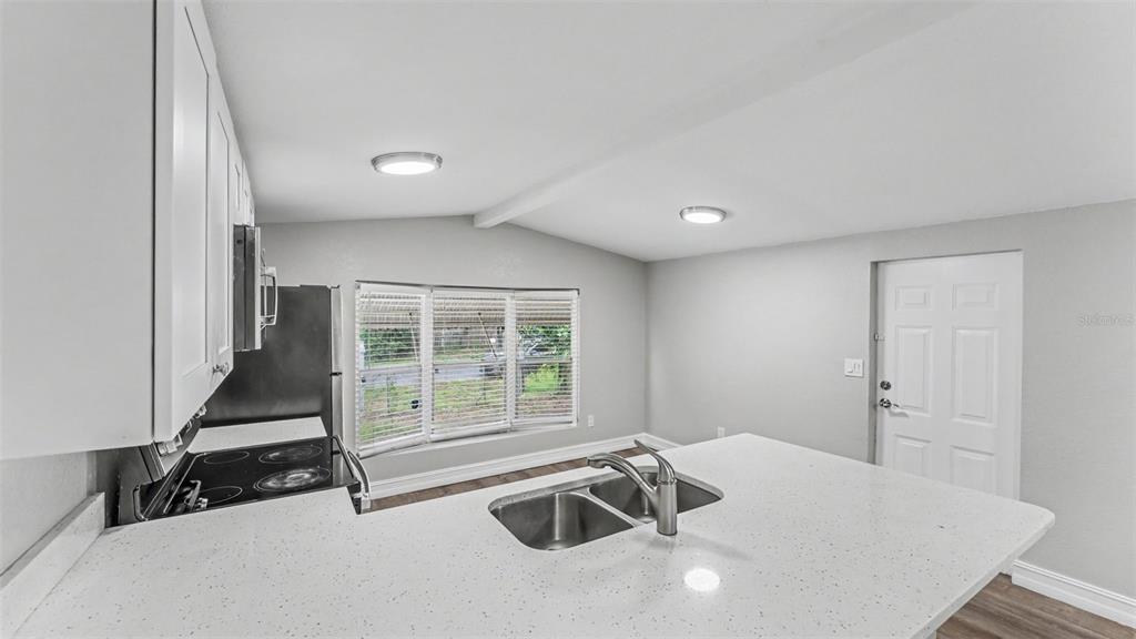 A kitchen features white cabinets, a quartz countertop island with a sink, and a window — 212 KAYLOR DRIVE, AUBURNDALE, FL