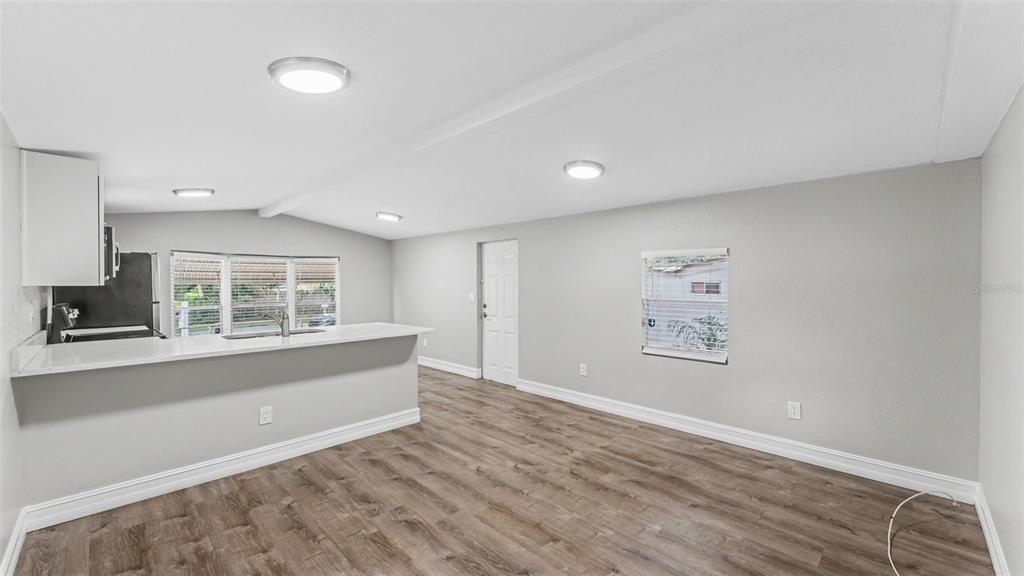 A kitchen with a breakfast bar opens into a living area with wood-look flooring — 212 KAYLOR DRIVE, AUBURNDALE, FL