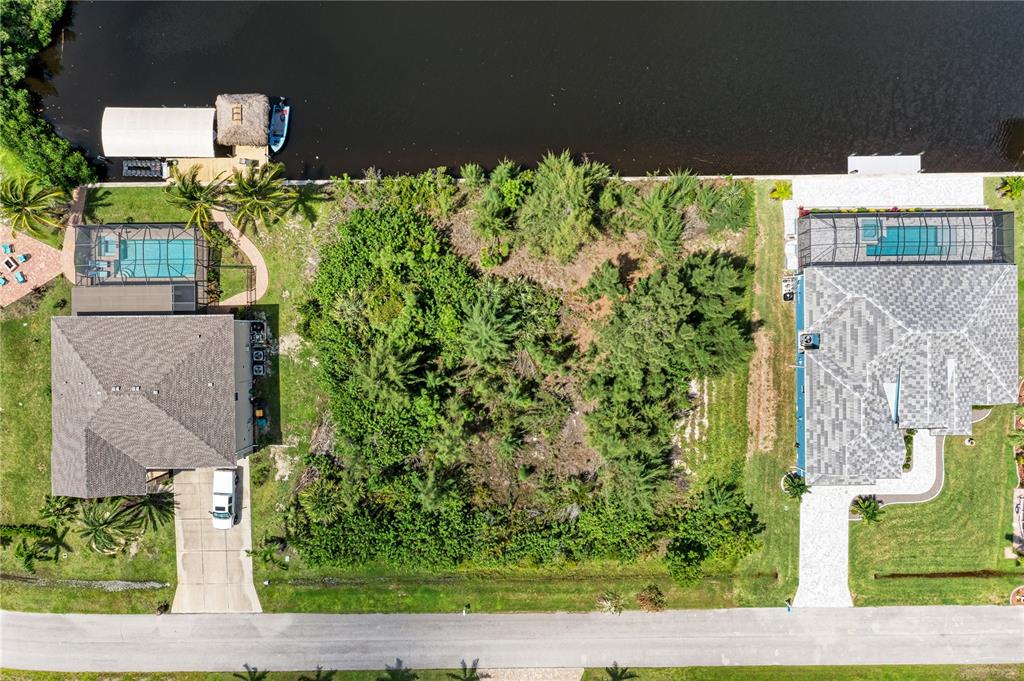 An aerial view shows a vacant lot situated between two houses along a canal — 15068 CHINOOK WAY, PORT CHARLOTTE, FL