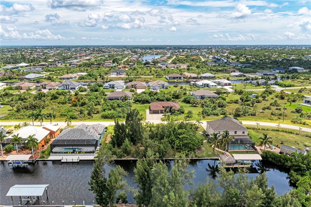 An aerial view shows waterfront houses with pools and boat docks along a canal — 15068 CHINOOK WAY, PORT CHARLOTTE, FL