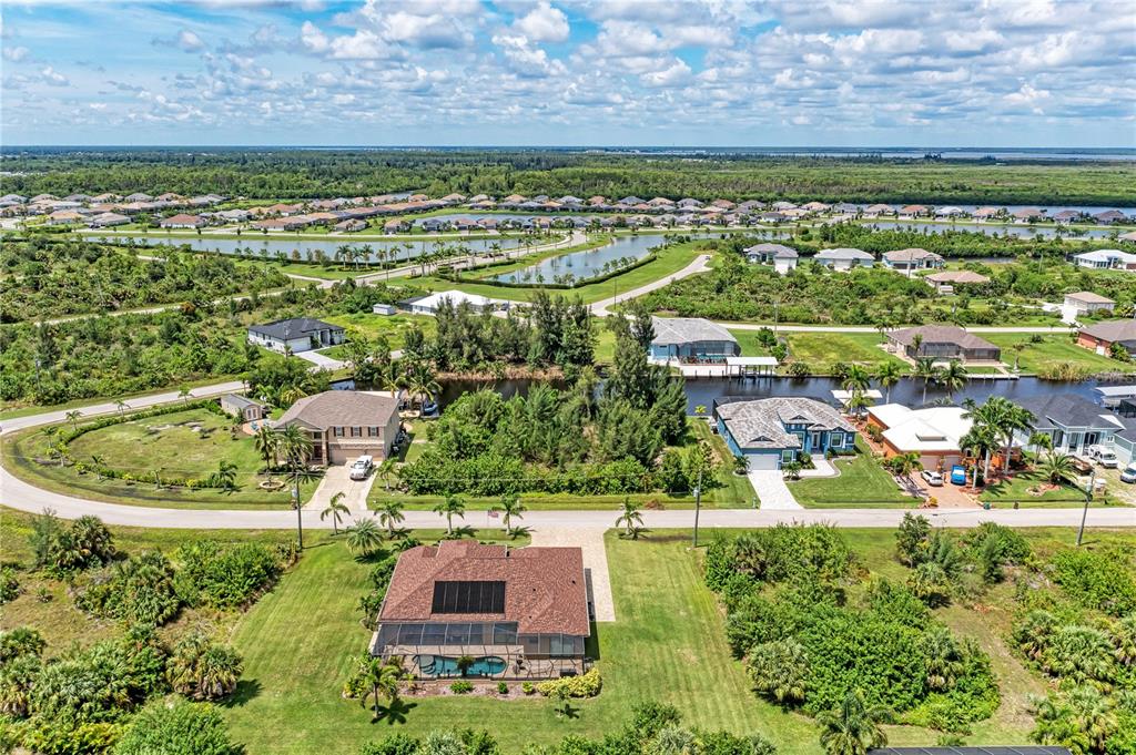 An aerial view shows a residential neighborhood with houses, swimming pools, and a canal — 15068 CHINOOK WAY, PORT CHARLOTTE, FL