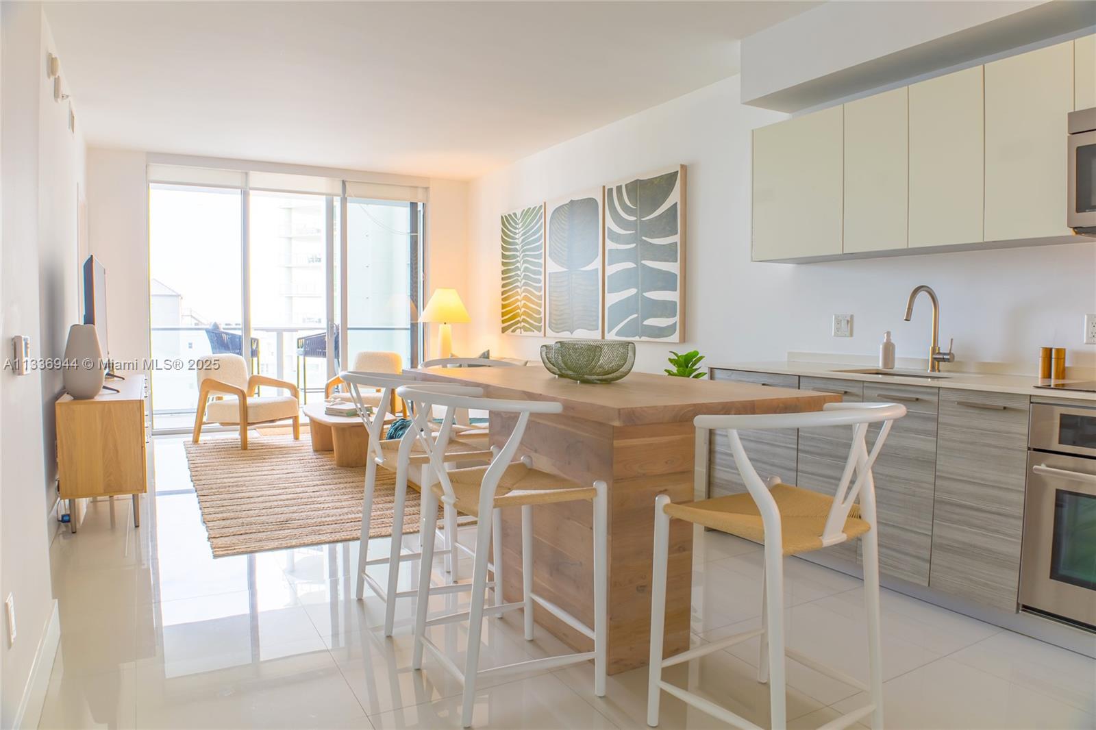 A modern open-concept kitchen and living area features a wooden island and white tile floors — 1300 Brickell Bay Dr # 1608, Miami FL 33131, MIAMI, FL