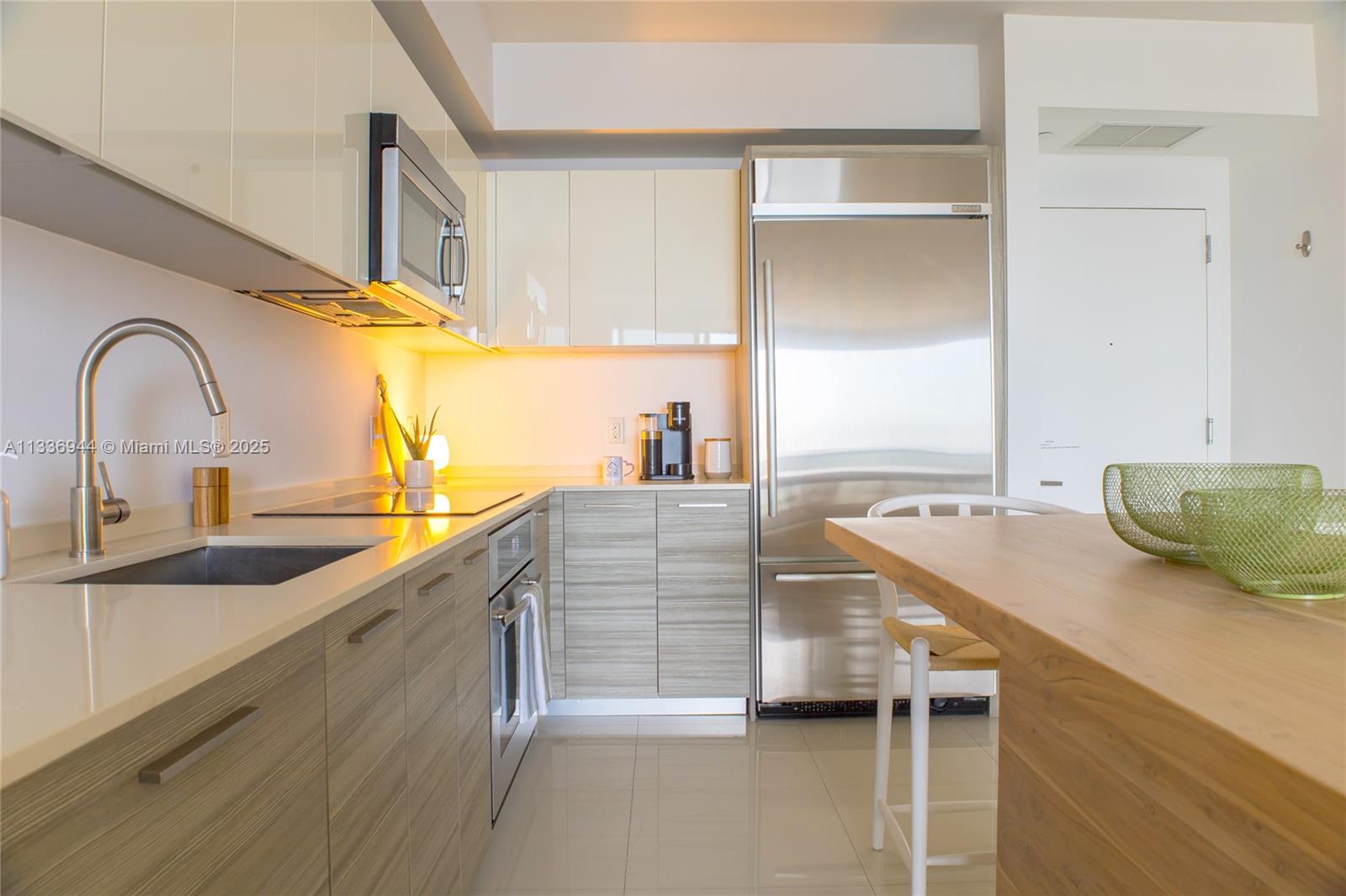 A modern kitchen features light wood-grain lower cabinets, white upper cabinets, and stainless steel appliances — 1300 Brickell Bay Dr # 1608, Miami FL 33131, MIAMI, FL