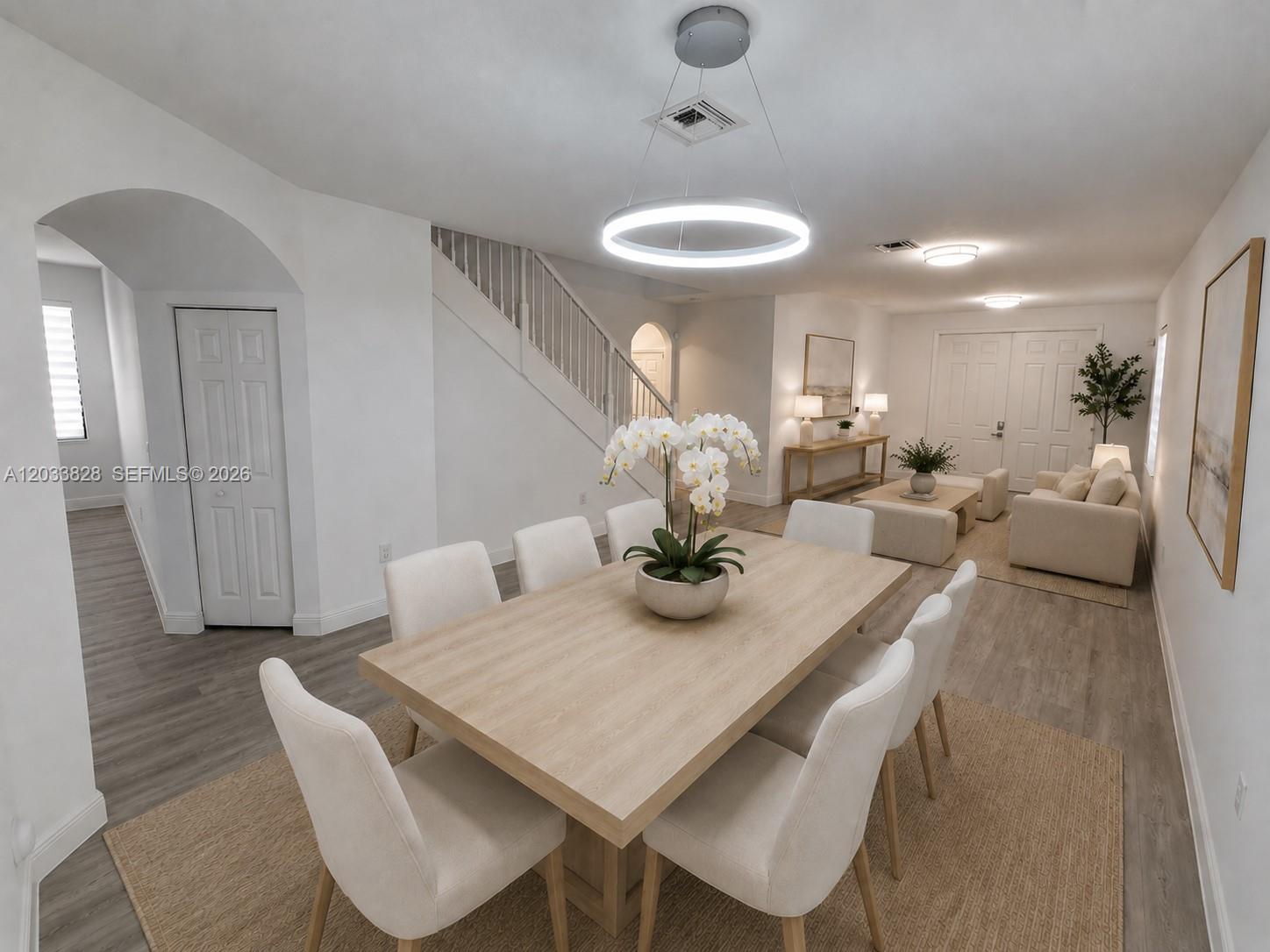A dining area with a light wood table and chairs sits before a living room — 8858 NW 101st Pl, Doral FL 33178, DORAL, FL