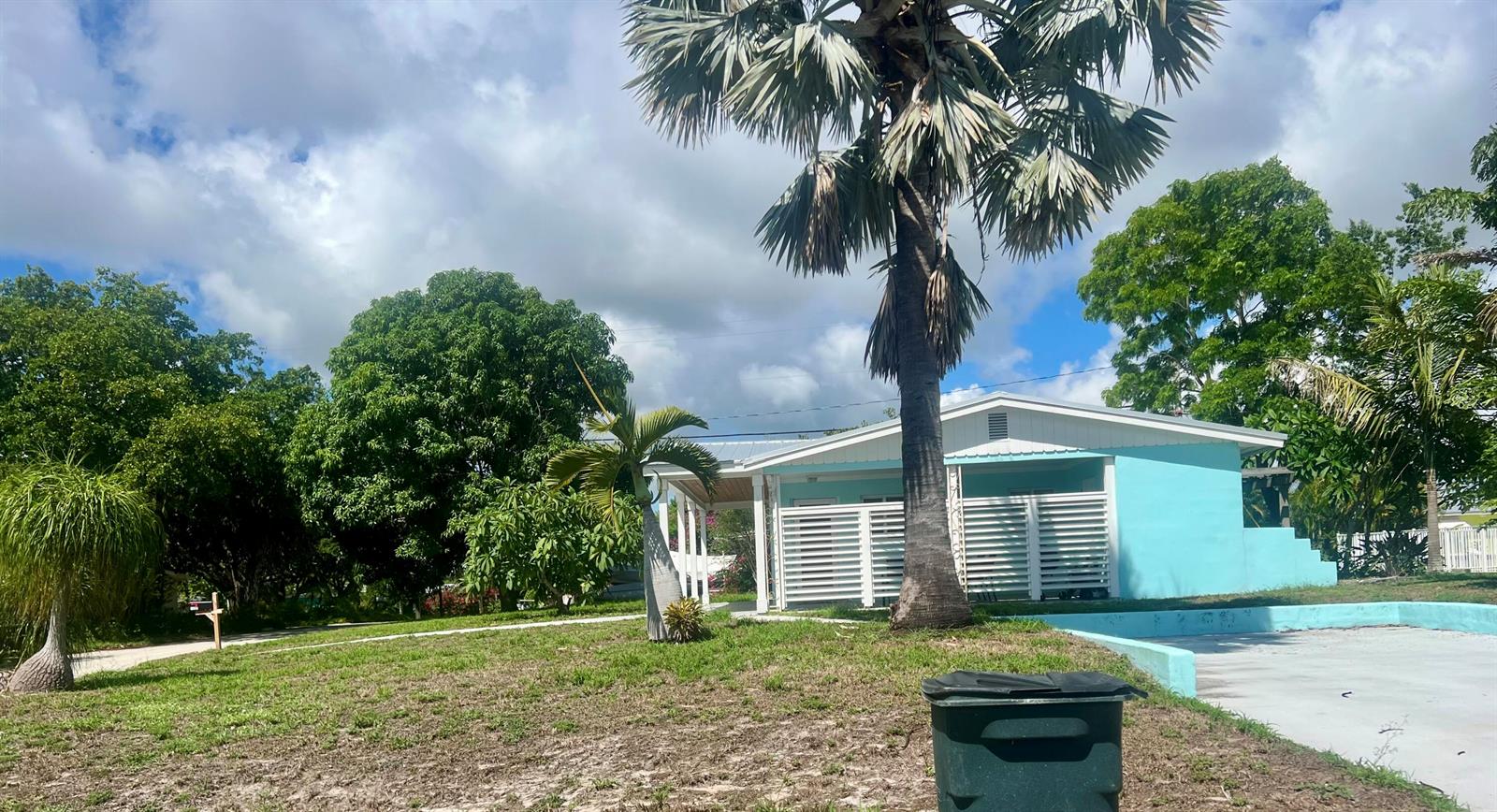 A light blue single-story house with white shutters sits on a grassy lot with palms — 1395 NE Flora Place, Jensen Beach FL 34957, JENSEN BEACH, FL