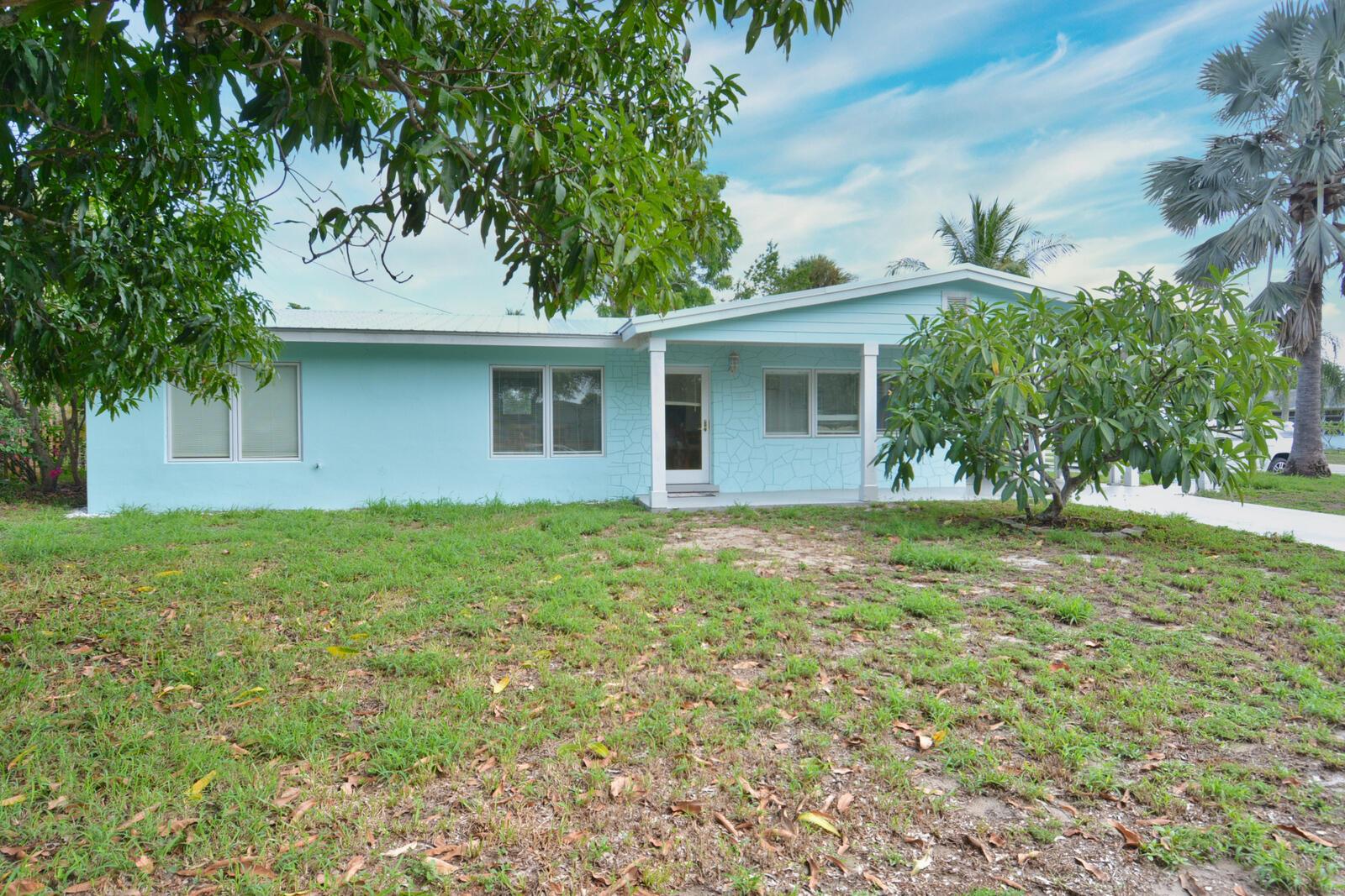 A light blue, single-story house with a front porch and a grassy yard — 1395 NE Flora Place, Jensen Beach FL 34957, JENSEN BEACH, FL