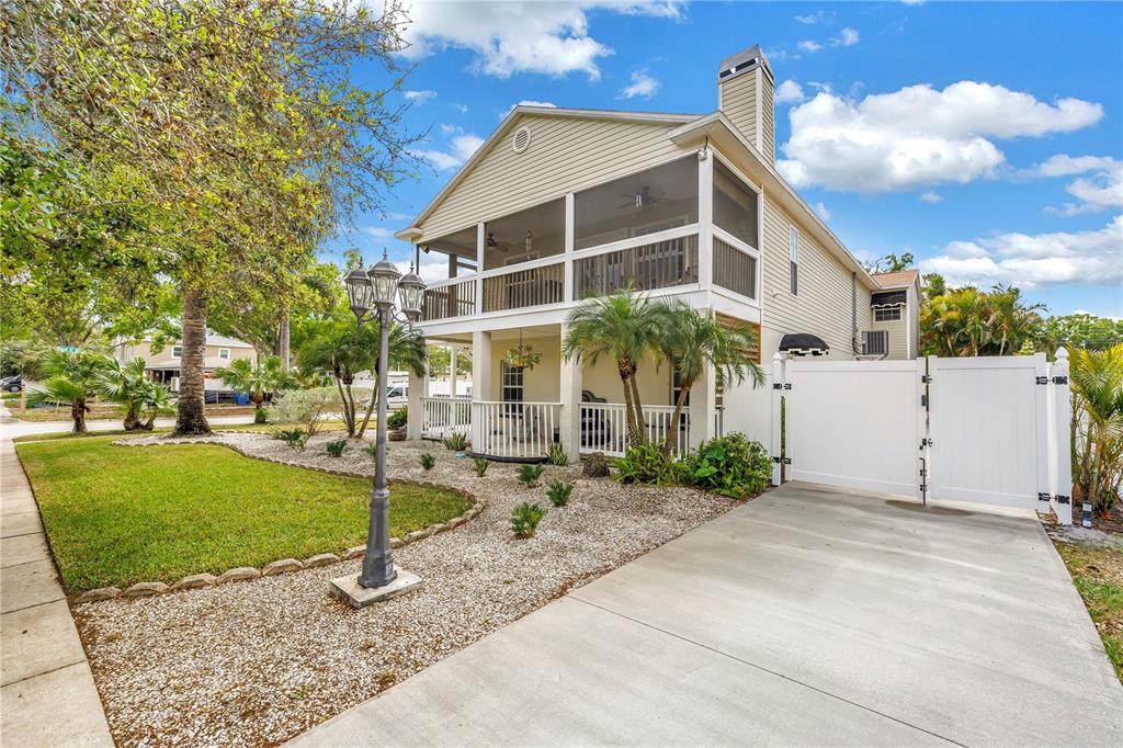A two-story house with a screened-in porch, a concrete driveway, and a white privacy gate — 786 59TH AVENUE NE, ST PETERSBURG, FL