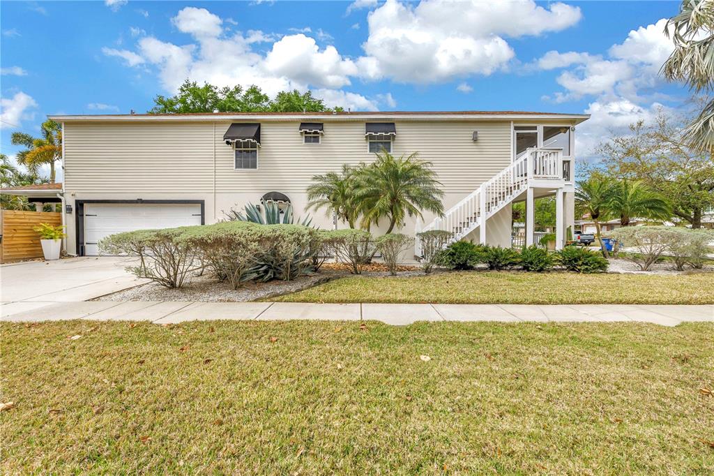 A two-story house with beige siding, a garage, and an exterior staircase leading to a deck — 786 59TH AVENUE NE, ST PETERSBURG, FL