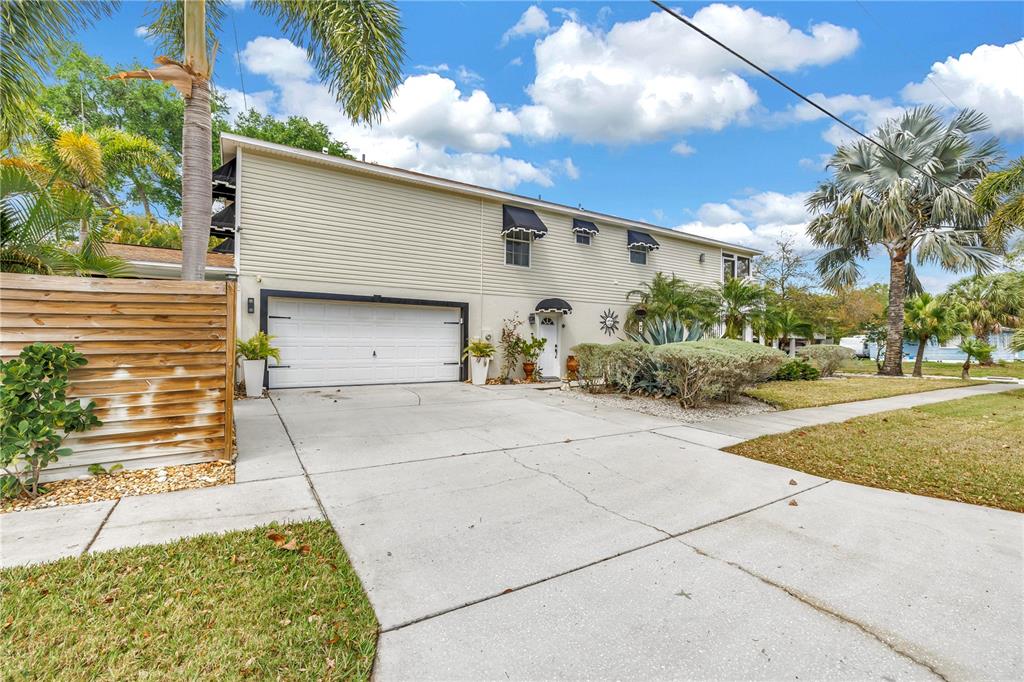 A two-story house with beige siding, a white garage door, and a concrete driveway — 786 59TH AVENUE NE, ST PETERSBURG, FL