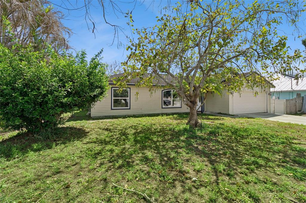 A single-story house with light-colored siding, a garage, and a large tree in the yard — 3349 SW FRANKFORD STREET, PORT ST LUCIE, FL